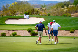 members playing golf and one hitting a putt at tee it up for the troops at desert mountain club