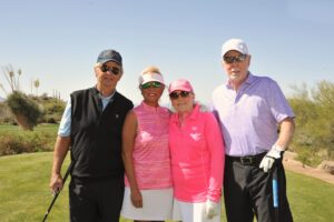 two men and two women standing and smiling on a golf course care's golf tournament for cancer research at desert mountain club