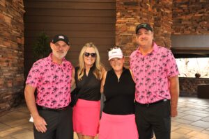 two men and two women standing and smiling after care's golf tournament for cancer research at desert mountain club
