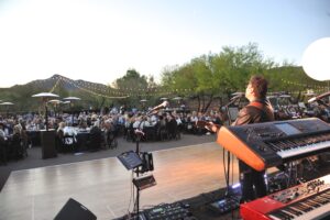 people sitting and watching and eating while listening to a band at care's rock for hope bash for cancer research at desert mountain club