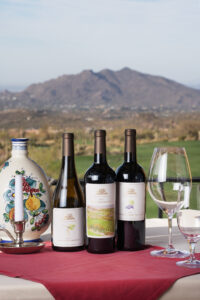 picture showing the three desert mountain club signature wines on a white table with a red cloth and a mountain in the background
