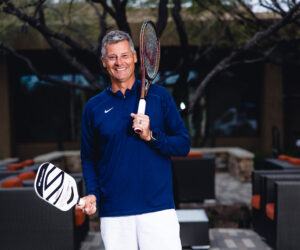 rich slivocka, director of racquet sports at desert mountain club in scottsdale smiles with a tennis racquet and pickleball paddle in hand