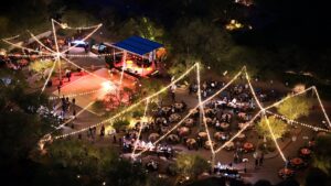 outdoor concert at night at desert mountain with string light and people sitting around tables
