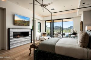 a bedroom of the many scottsdale homes at desert mountain with a small fireplace adjacent to a white bed with square steel framing