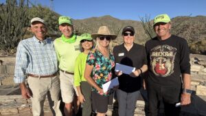 a group of six people standing outside a conservation area at desert mountain