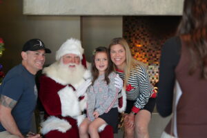a family taking a picture with santa clause in front of a fire place at desert mountain club