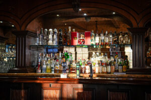 the bar at chiricahua clubhouse at desert mountain club with tequila and whisky bottles on a high shelf, sunlight is illuminating the dark wood interior