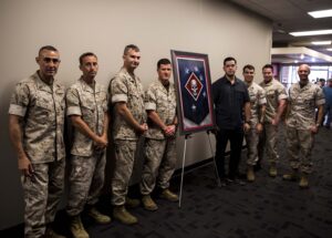 ellison keomaka standing with marines by his painting for the marine raiders