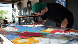 ellison keomaka drawing bright colorful flowers on a canvas for use in an art show