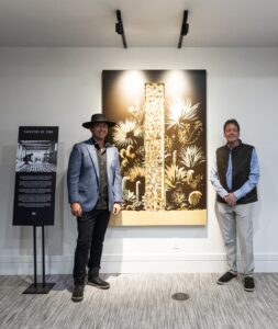 ellison keomaka standing in front of his artwork, tapestry of time, at the russ lyon office at desert mountain club