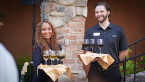 a female and male server holding drinks at an event at desert mountain club in scottsdale arizona