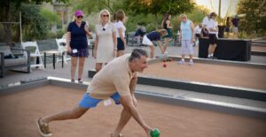 stef cugno rolling ball during a game of bocce at desert mountain with other members standing by and watching